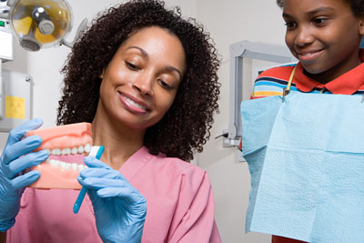 Odontologia pediátrica: pode-se ver uma odontopediatra ensinando uma criança a praticar escovação