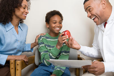 Odontologia pediátrica: na imagem é possível ver um odontopediatra mostrando uma maçã ao menino