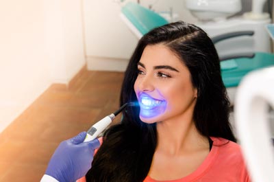 Benefícios do clareamento dental: a jovem está passando pelo tratamento de clareamento a laser.
